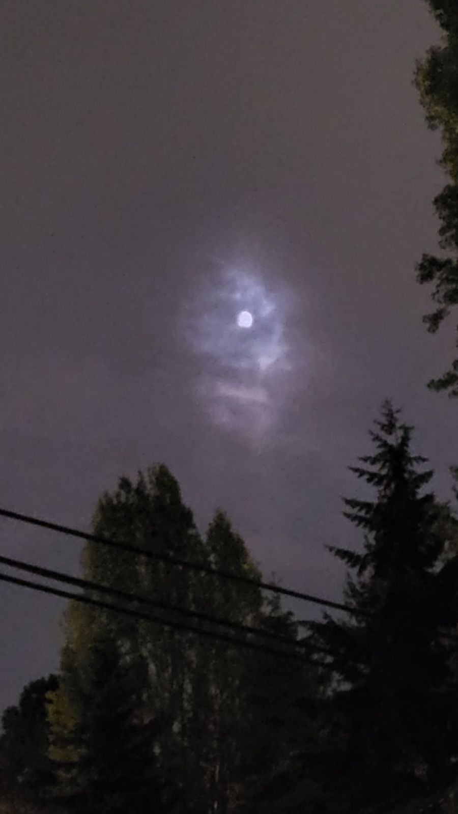 A cloud passing over the moon, illuminated, creates the shape of a skull with its mouth open. The moon sits between the two eyes.