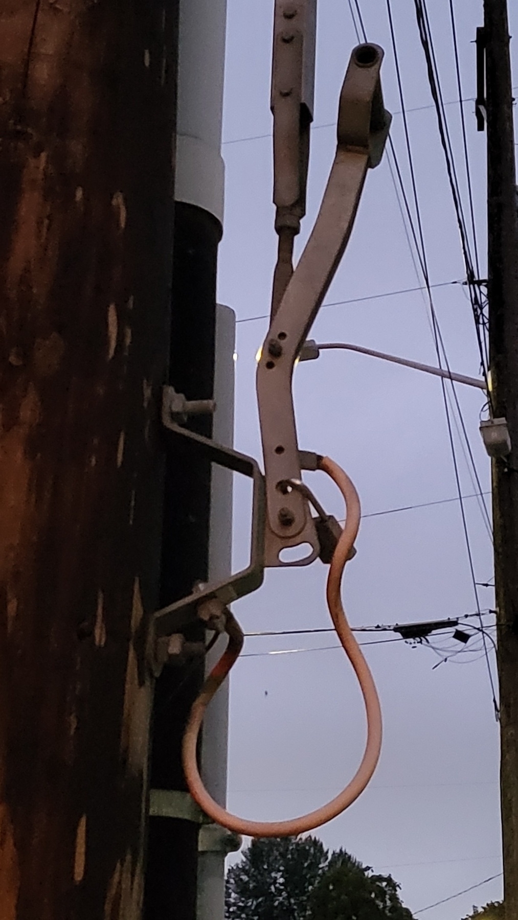 The side of a lamp pole. A wire makes a curved shape like the body of a guitar. A fuse switch lever thing makes the neck.