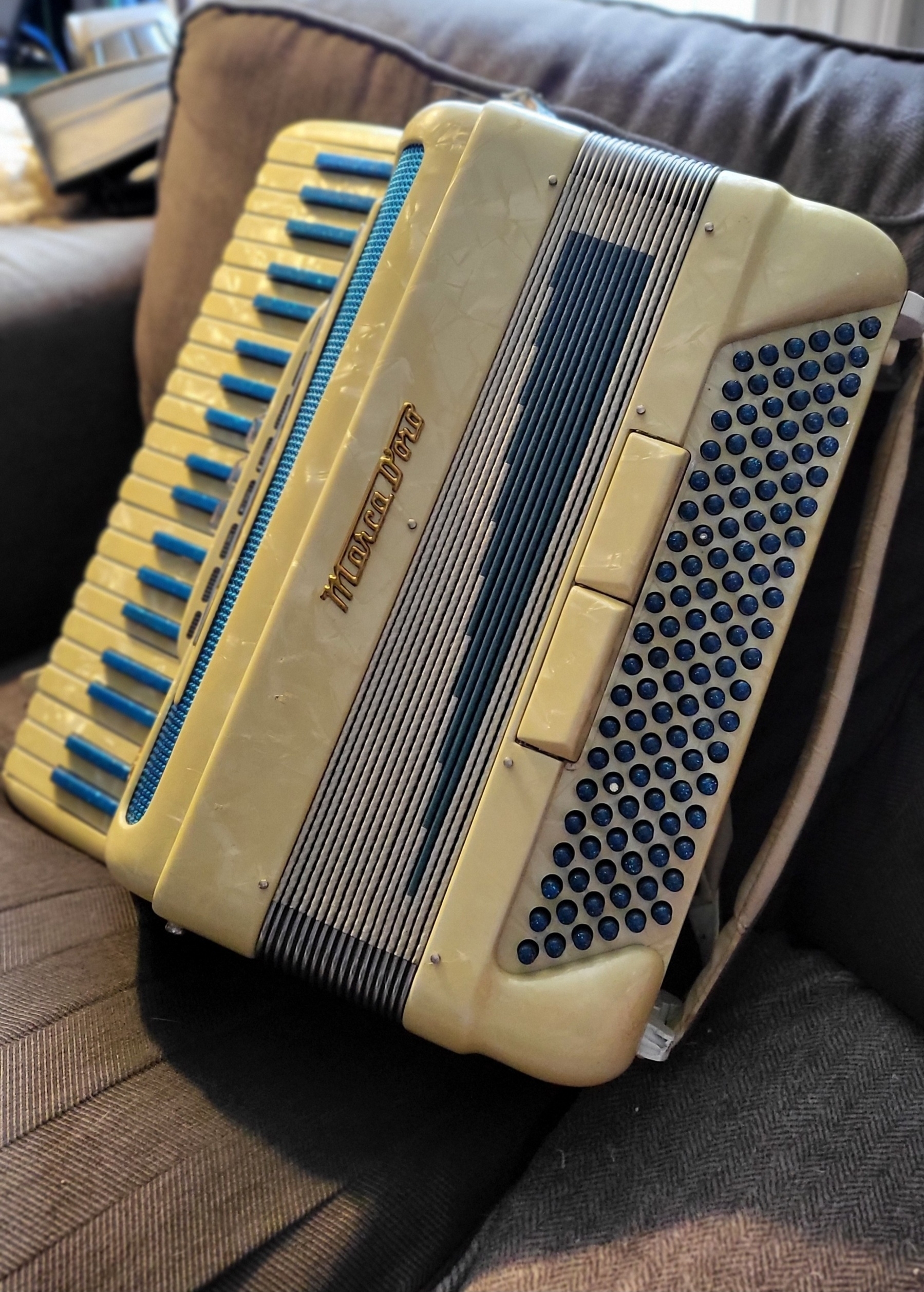 Italian accordion with blue buttons and keyboard keys. Gold lettering labels it as Marco D'Oro.